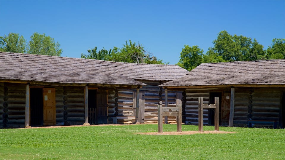 A log cabin with a wooden fence and a wooden sign in front.