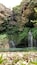 A waterfall cascading into a clear pool surrounded by rocky cliffs and lush greenery.