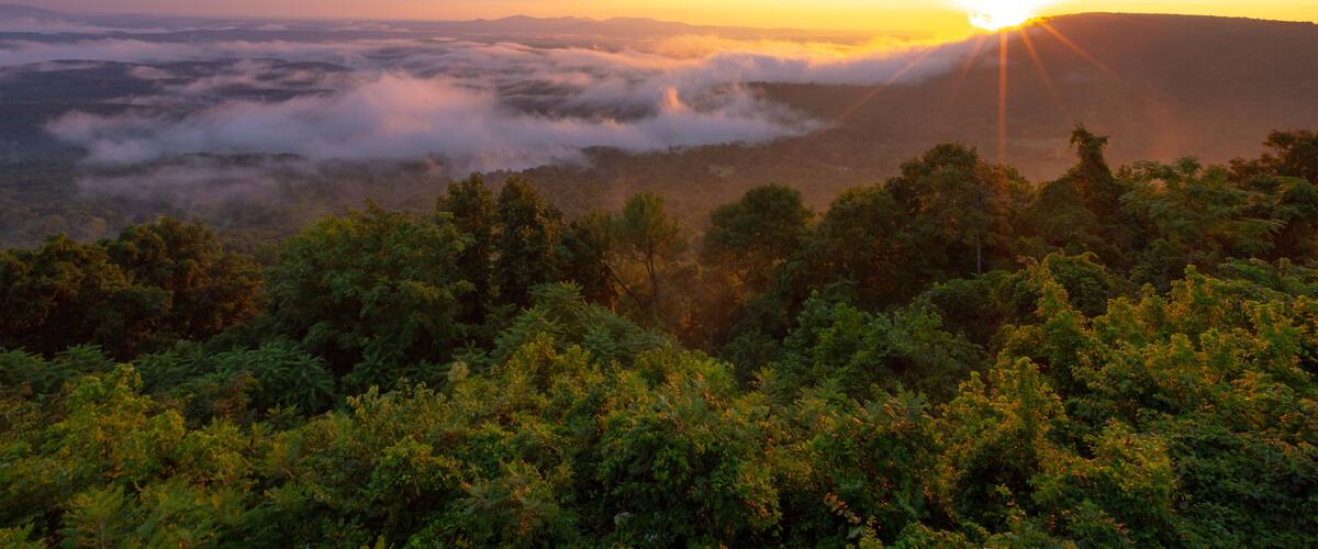 Morning sun rays through clouds and fog over mountains at Arkansas Grand Canyon Scenic Overlook