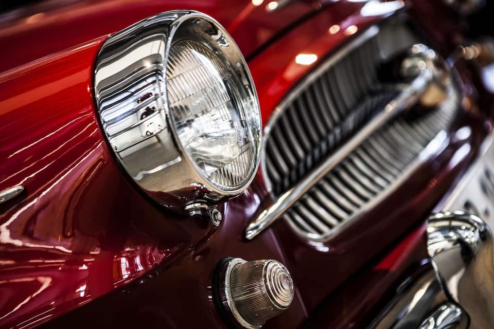 A close-up of a classic car's chrome grille and headlight.