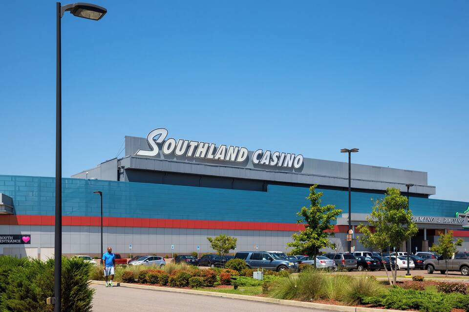 A Southland Casino building with a blue and red facade, surrounded by parked cars and greenery.
