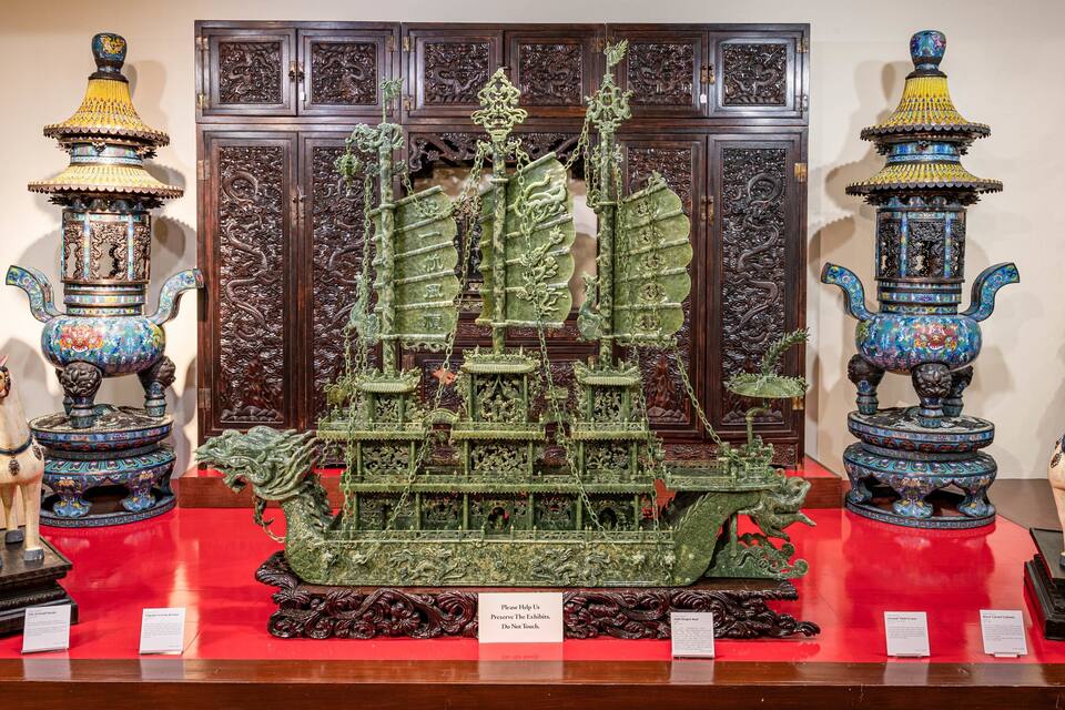 A detailed model of a traditional ship with ornate decorations and two horse statues on either side.