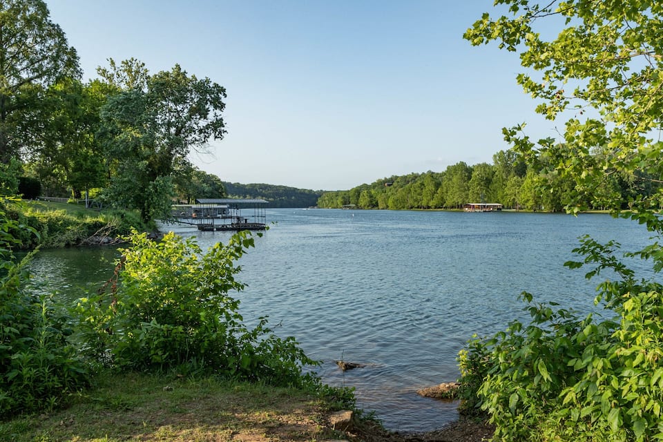 A lake surrounded by lush greenery, a dock, and a small boat.