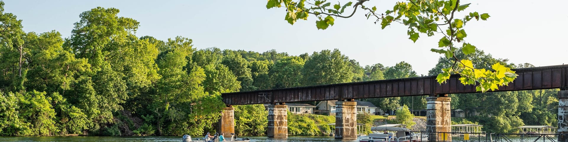 A bridge over a river with boats and people on the water.