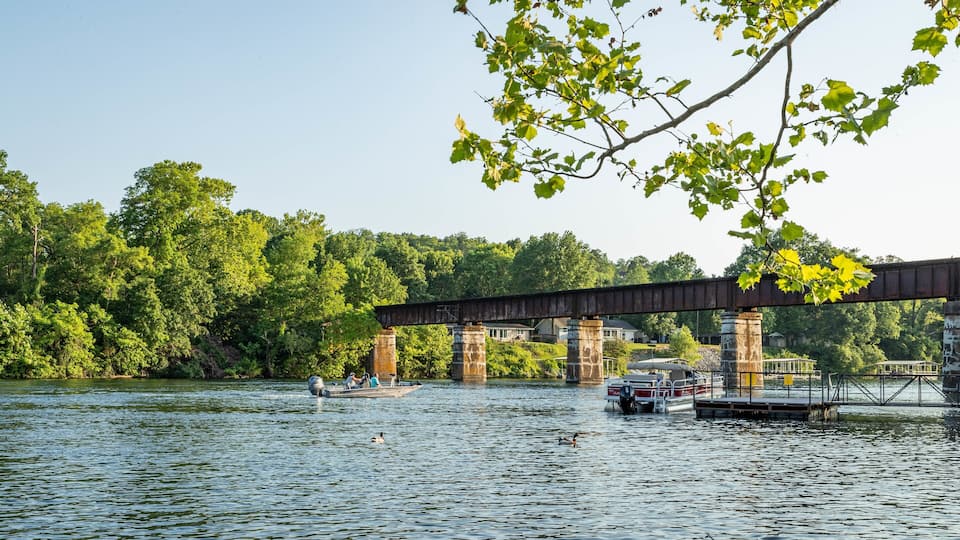 A bridge over a river with boats and people on the water.