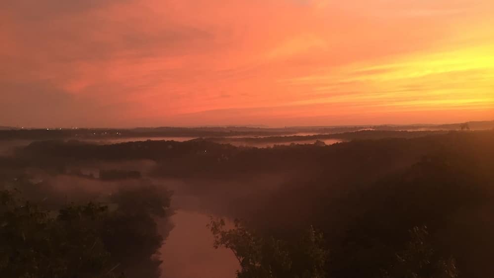 A sunset over a river with surrounding vegetation.