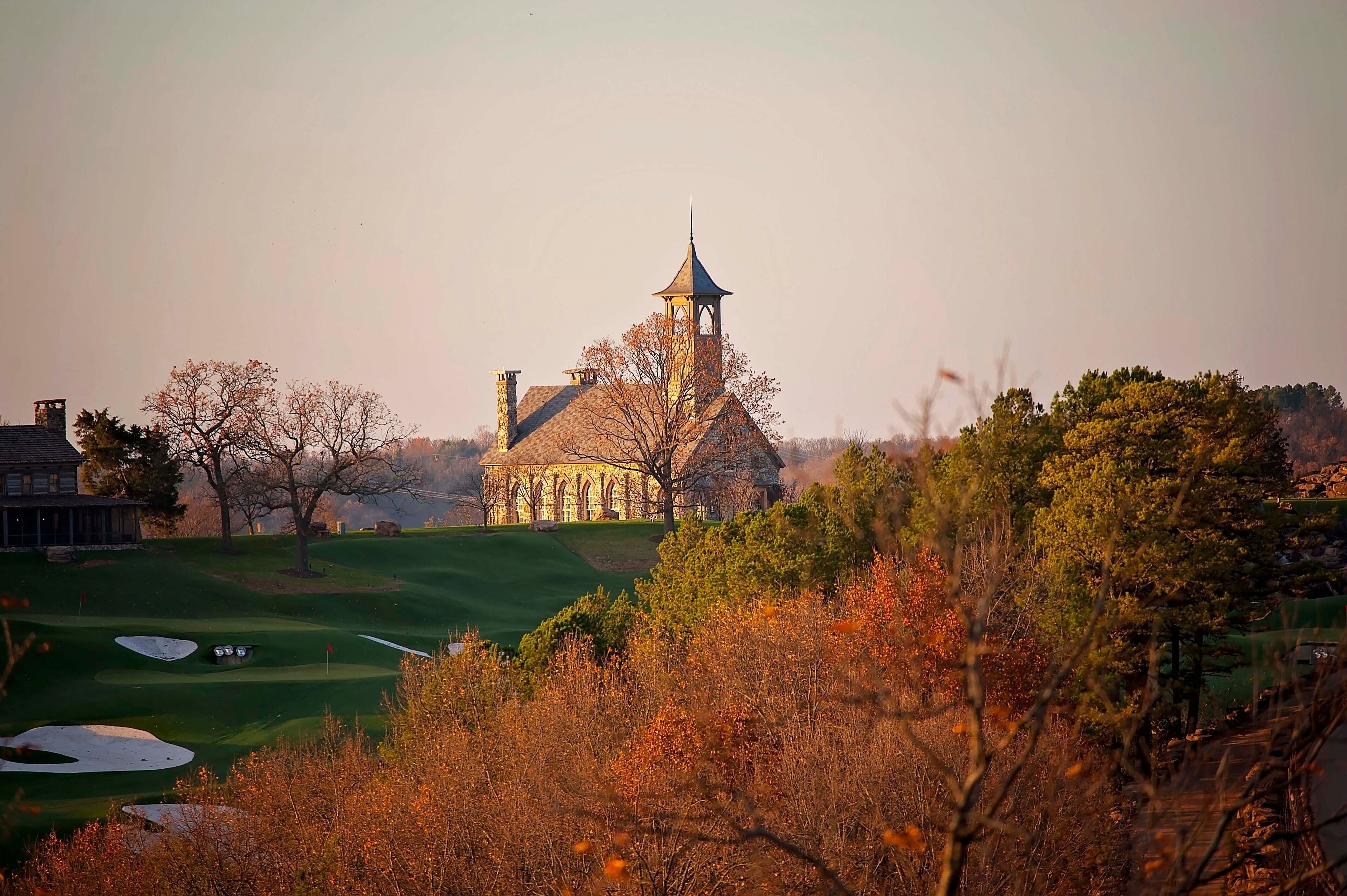 Stone chapel on a hill surrounded by autumn foliage at sunset