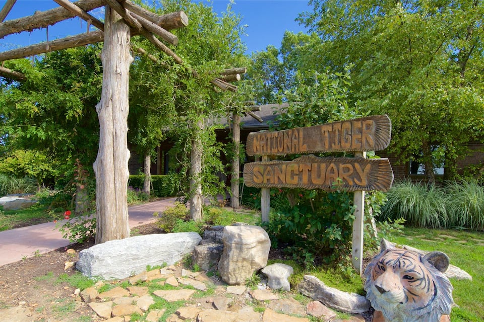 A wooden sign for the National Tiger Sanctuary surrounded by rocks and greenery.