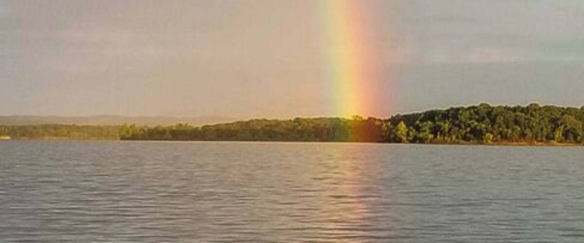 A rainbow over a body of water with a distant shoreline.