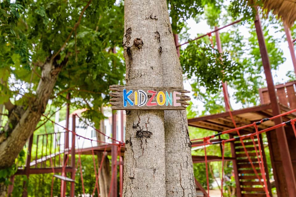 Een houten bord met kleurrijke letters waarop ‘KIDZONE’ staat.