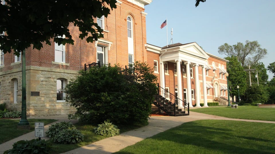 A historic brick building with a white portico and an American flag.
