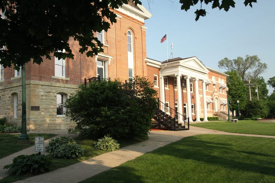 A historic brick building with a white portico and an American flag.