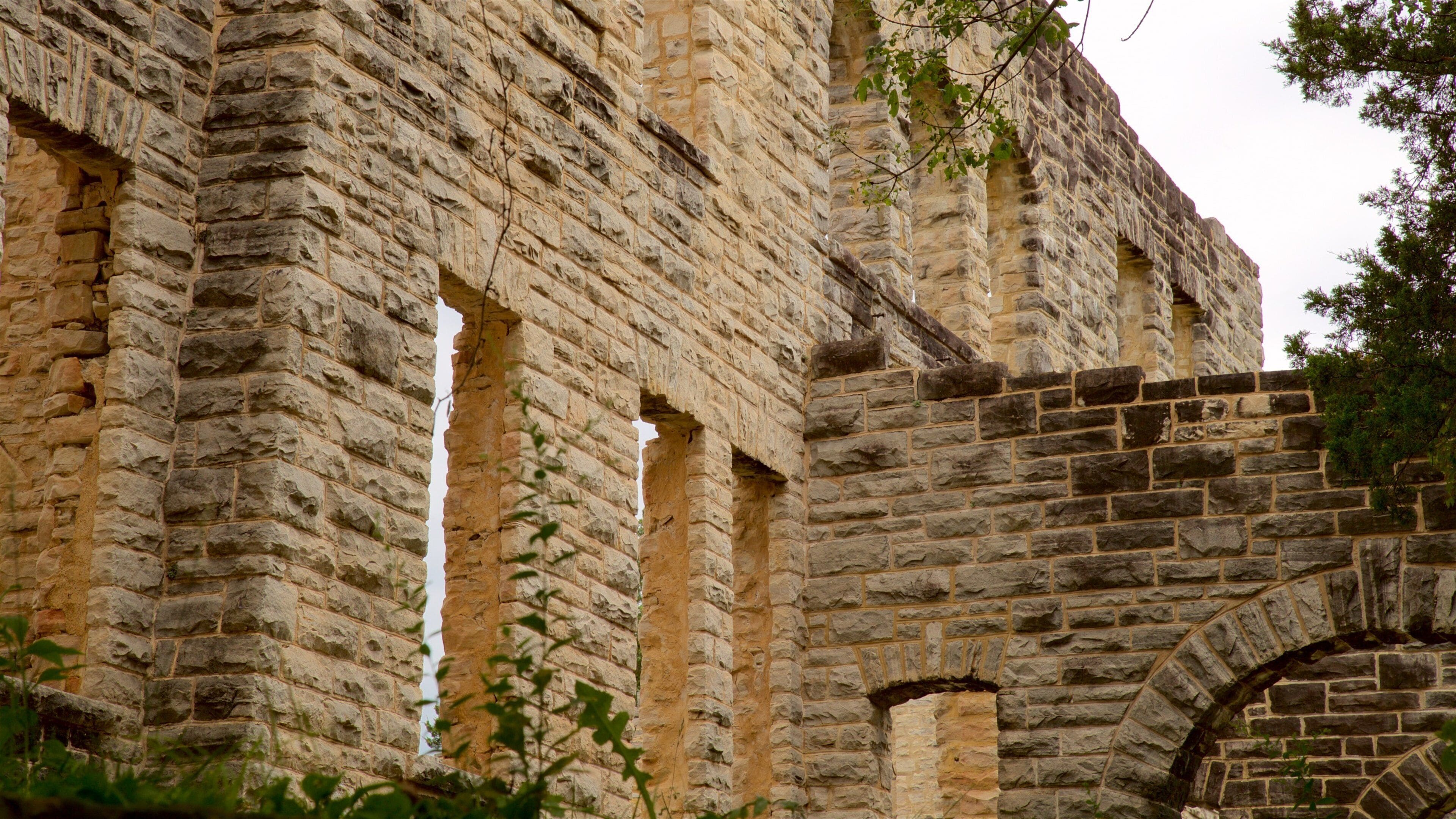 A stone building with arched windows and a brick archway.