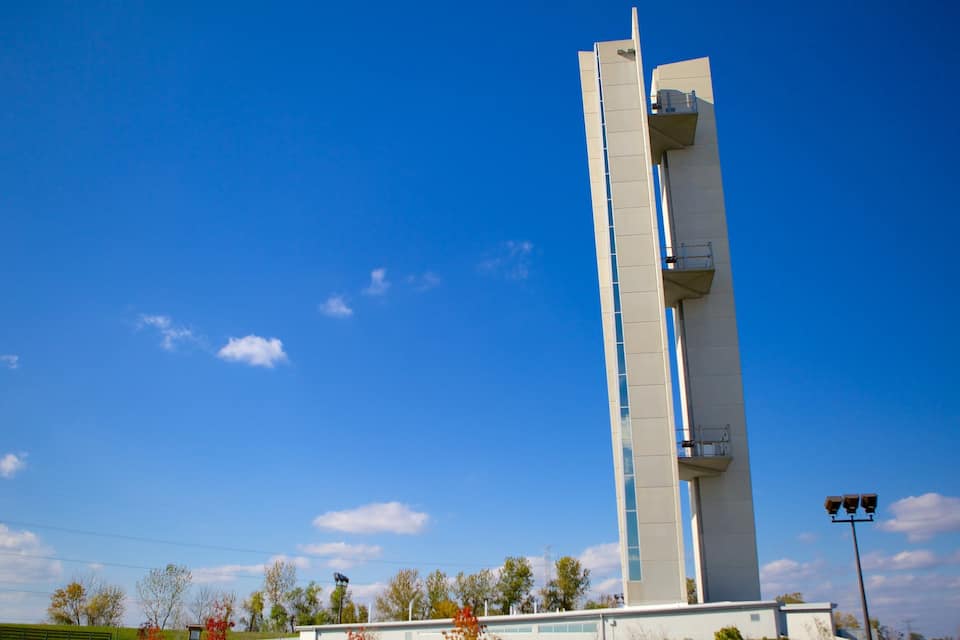 A tall, modern tower with a unique design, set against a clear blue sky with a few clouds.