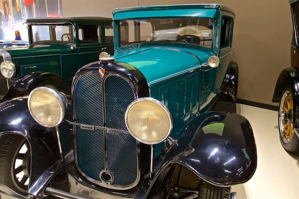 A vintage car with a teal body and black accents, including round headlights and a prominent grille.