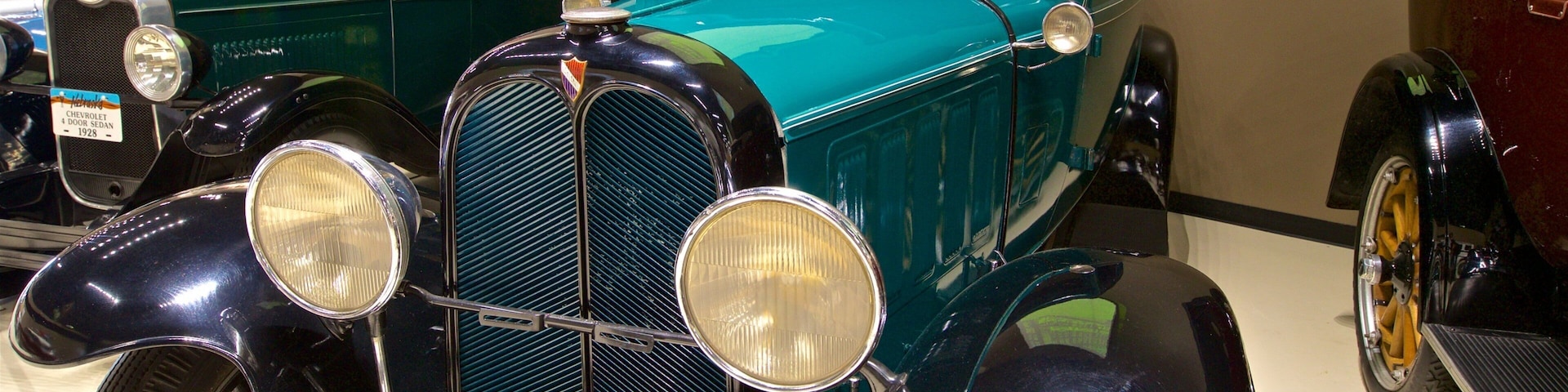 Um carro antigo com carroceria azul-turquesa e detalhes em preto, incluindo faróis redondos e uma grade frontal imponente.