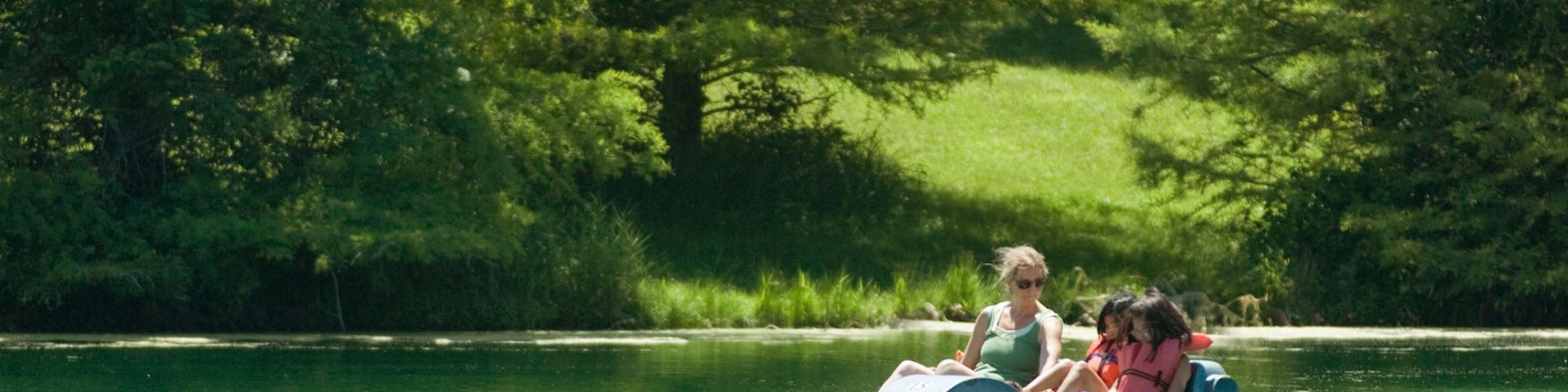 A small boat on a calm river surrounded by dense green trees.