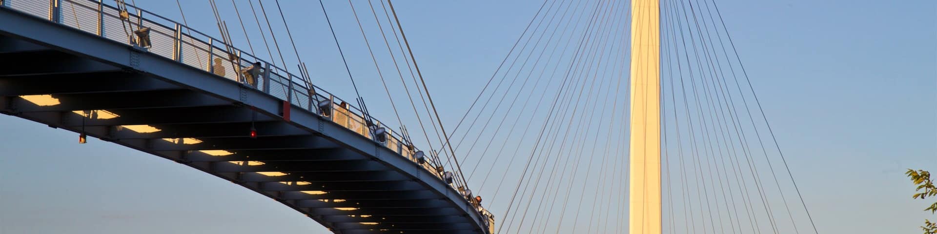 A cable-stayed bridge with a tall central tower and a pedestrian walkway.