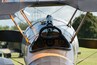 The cockpit of an old biplane with a wooden steering wheel and gauges.