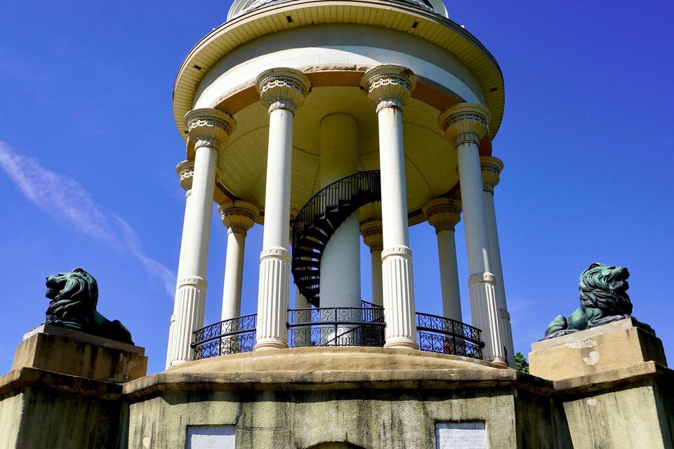 A historical building with a central dome, flanked by columns, and statues on either side.
