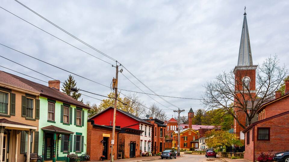 A historic street with colorful buildings, a church steeple, and a red-roofed building.