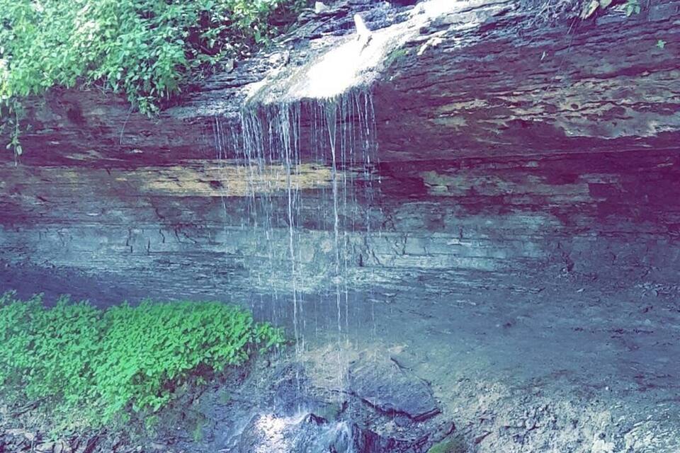A waterfall cascading over a rocky cliff with green vegetation at the base.
