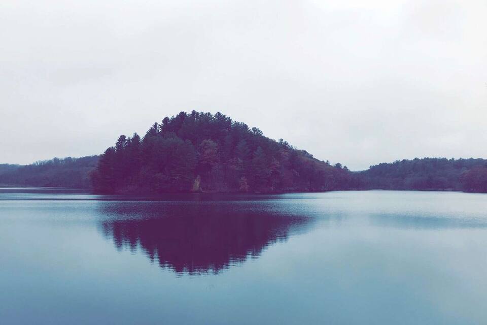 A calm lake with a small island covered in trees.