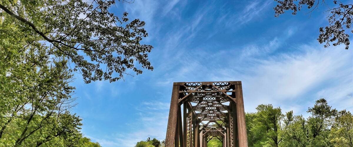 Beneath a blue sky with white clouds on a summer day in Wisconsin, an old train trestle has been converted to carry only hikers and bikers across a Mississippi backwater on the Great River Trail.