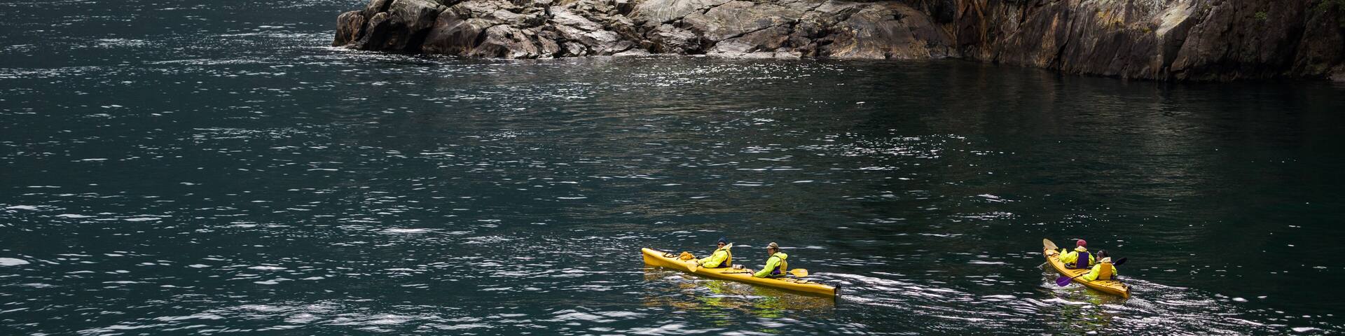 Kayakers enjoy the scenery and waterfalls of Milford Sound, one of New Zealand's most popular tourist destinations
