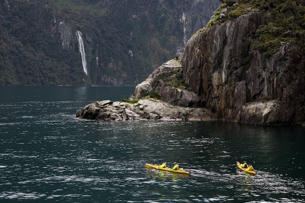 Kayakers enjoy the scenery and waterfalls of Milford Sound, one of New Zealand's most popular tourist destinations
