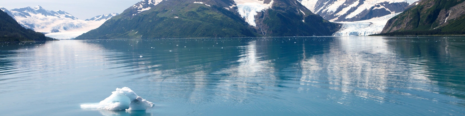 Un groupe de personnes à bord d’un bateau, observant un glacier dans un lac de montagne.