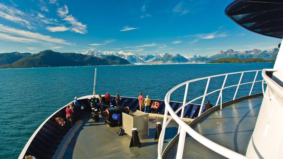 A boat on a calm lake with snow-capped mountains in the background.