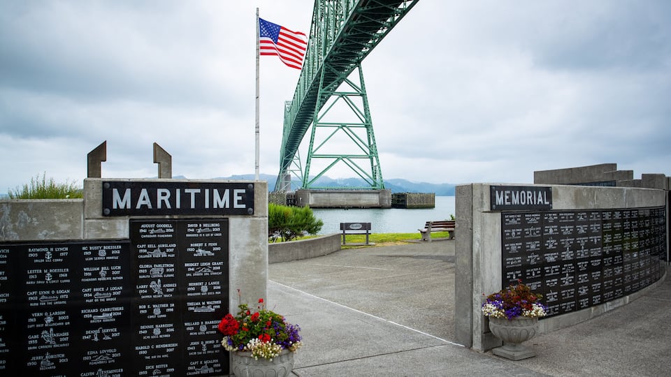 A memorial with names and dates, a bridge, and an American flag.