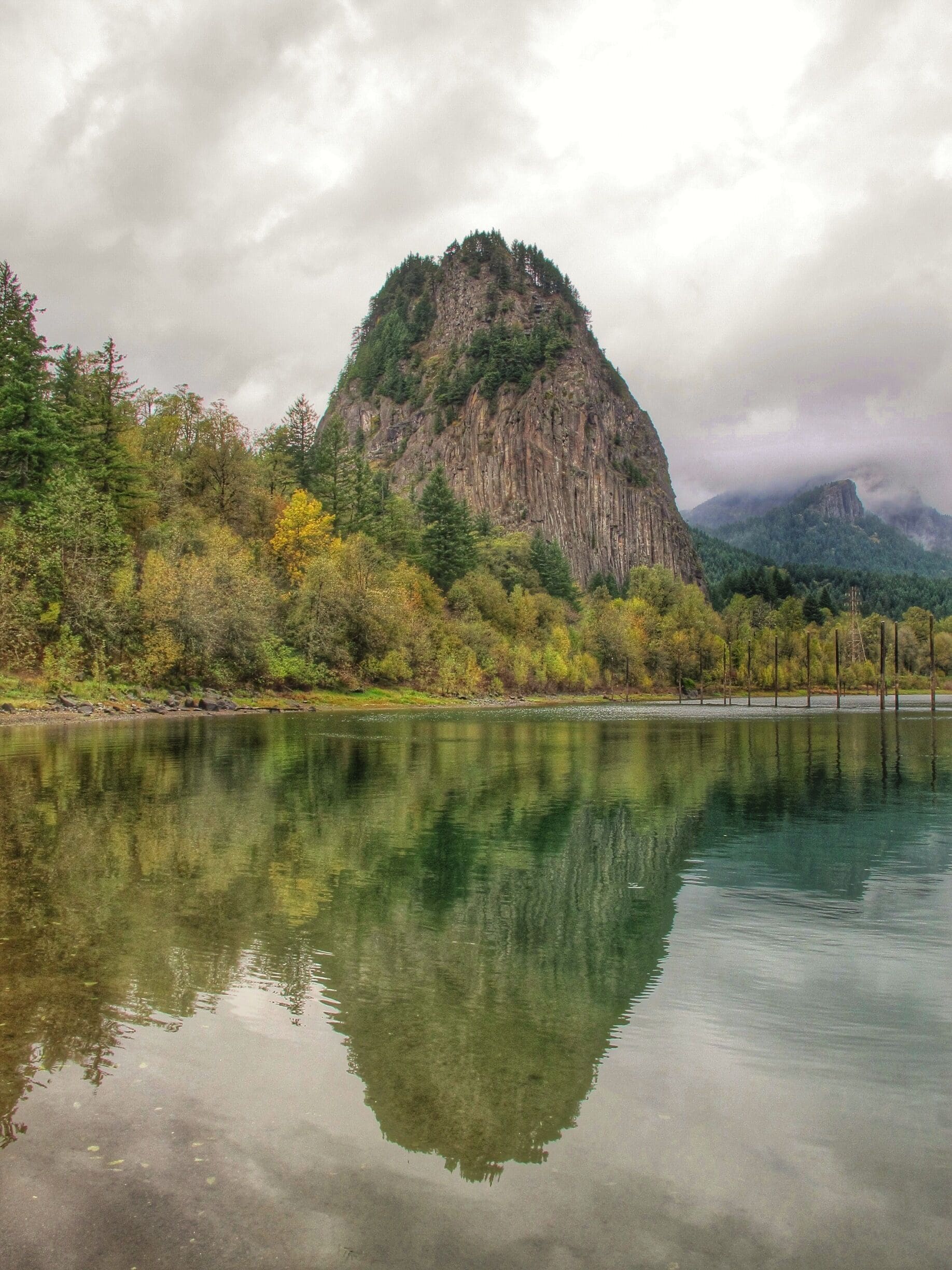 A mountain with a lake in the foreground reflecting the mountain and trees.