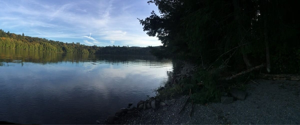 A calm lake with a forested island in the center, surrounded by rocky shores.