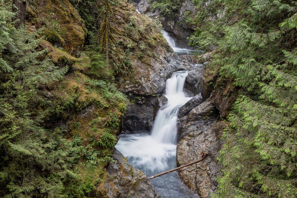 A waterfall cascading through a rocky gorge surrounded by dense green foliage.
