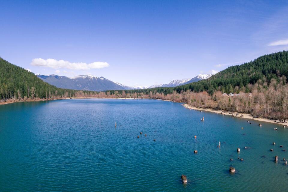 A river surrounded by forested mountains and a clear sky.