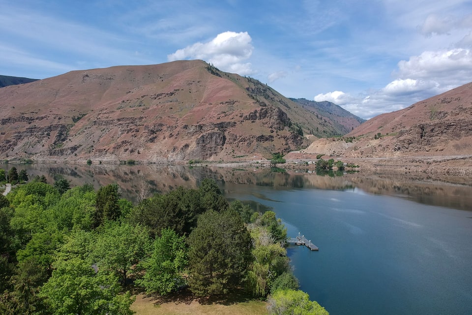 A lake surrounded by mountains with a dock extending into the water.