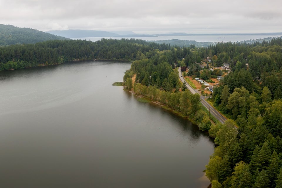 A large lake surrounded by dense forests and a few houses.