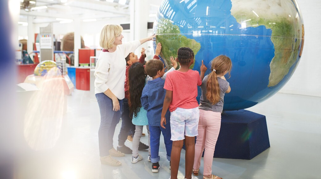 Teacher and students touching large globe in science center