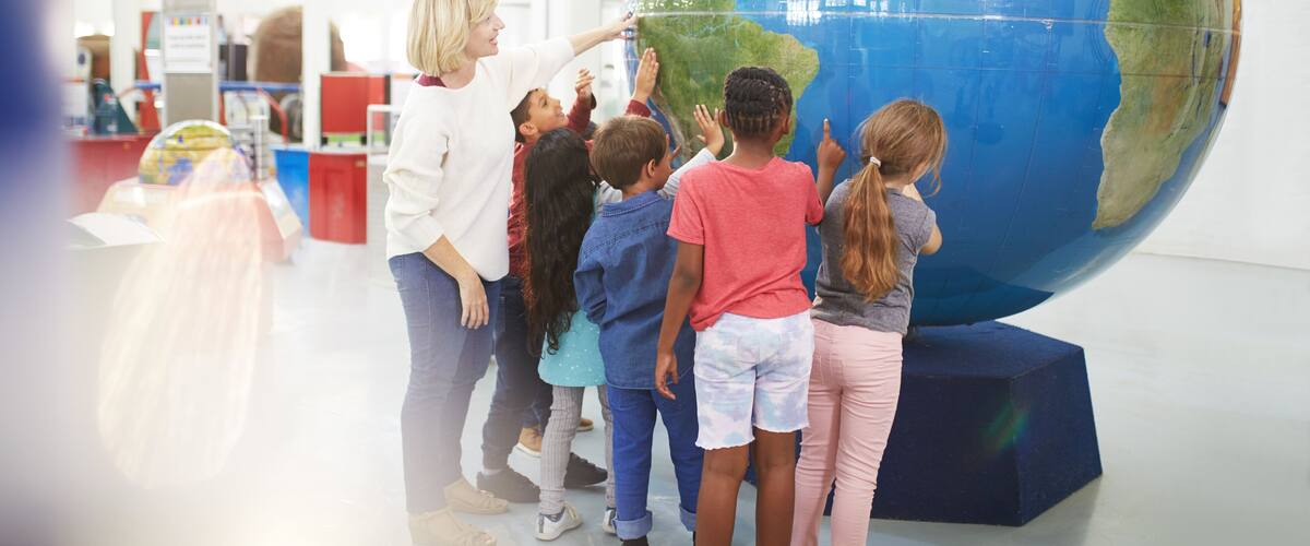 Teacher and students touching large globe in science center