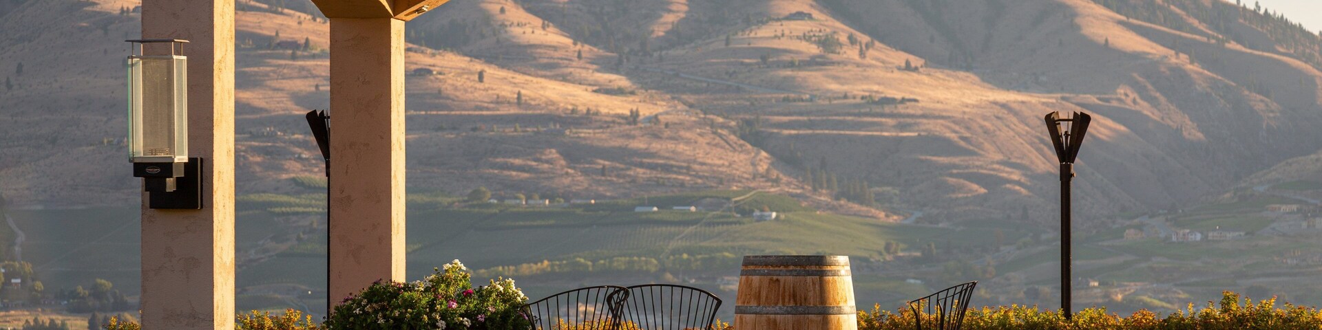Una pérgola con vistas a colinas onduladas y un barril grande.