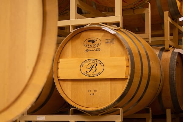 Barricas de vinho de madeira empilhadas num armazém.