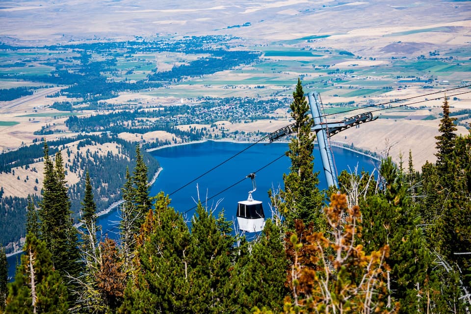 A cable car system over a lake surrounded by forested hills.