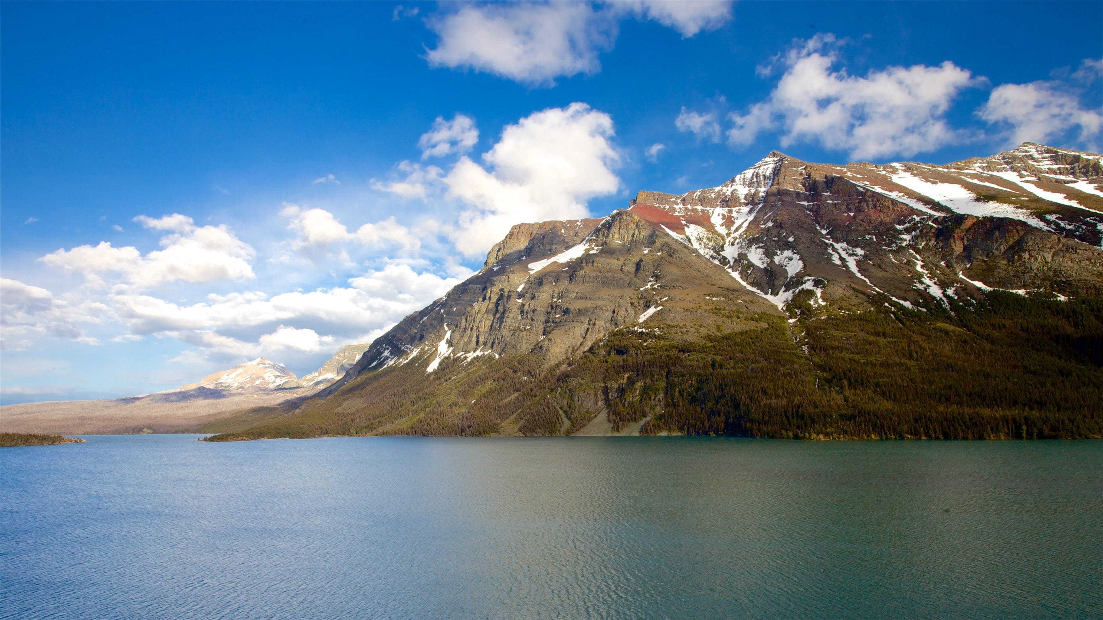 St. Mary Lake which includes mountains, a river or creek and landscape views