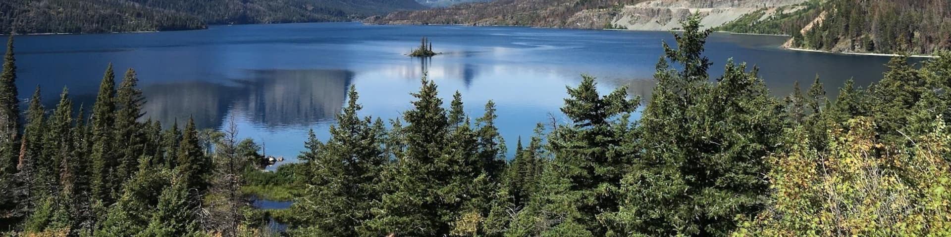 Un lac de montagne entouré de pics escarpés et d’une forêt dense.