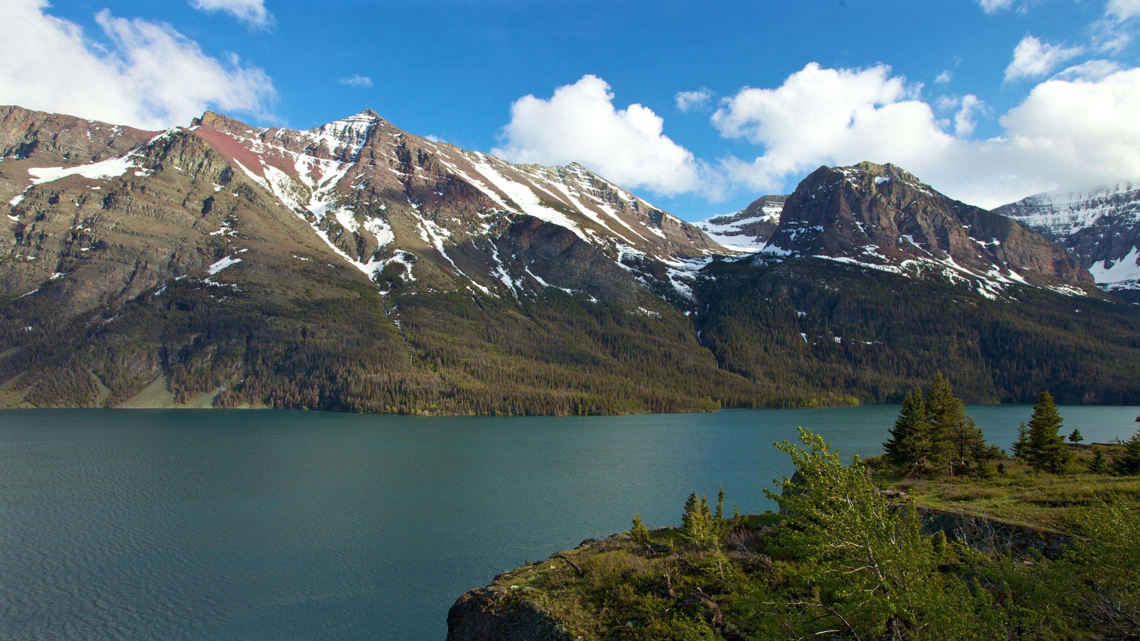 A mountain range with snow-capped peaks and a calm lake.