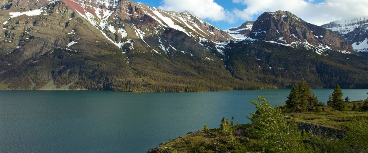 A mountain range with snow-capped peaks and a calm lake.