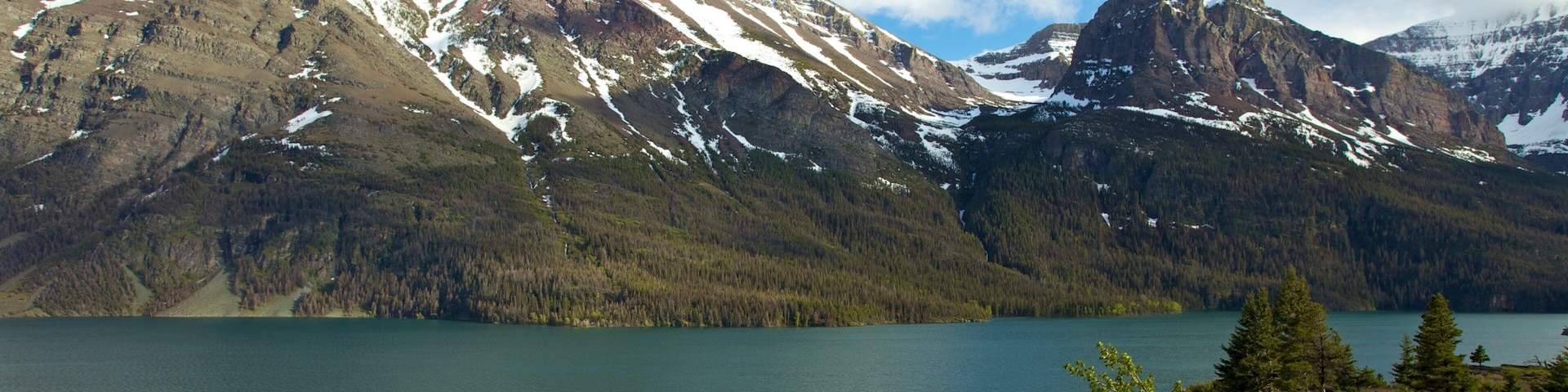 A mountain range with snow-capped peaks and a calm lake.