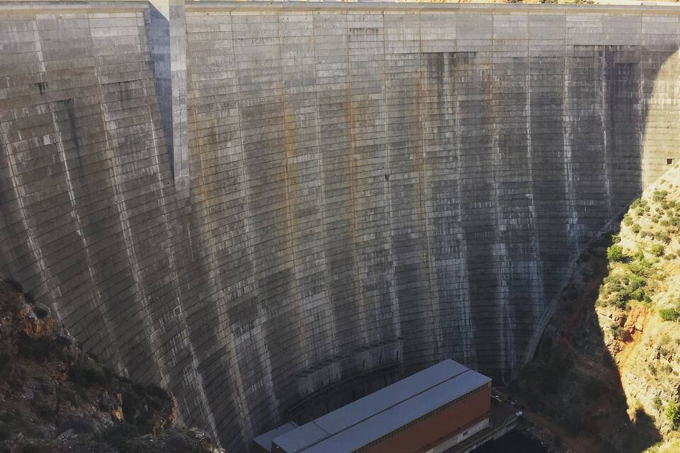 A large dam with a concrete structure and a small building at its base.